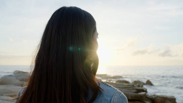 istock Clouds, sky and woman with calm on beach for relax, zen or mindful vacation with sunrise. Breathing, peace and back of female person by island, ocean or sea on holiday or weekend trip for travel. 2149043003