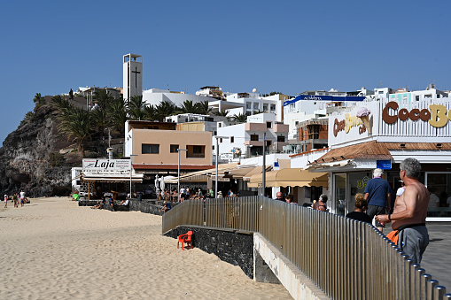Jandia / Morro Jable, Fuerteventura, Spain, February 18, 2024 - Tourists on the beach promenade and in cafés on the town beach of Morro Jable, Playa de la Cebada / Playa del Matorral, Fuerteventura