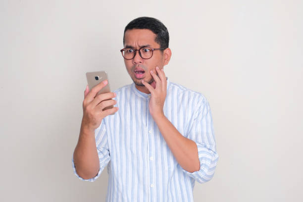 istock Adult Asian man showing scared face expression when looking to phone that he hold 2149047981