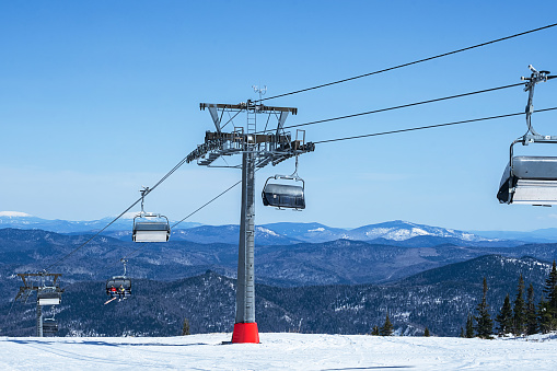 Chairlift in mountains during sunny winter day.