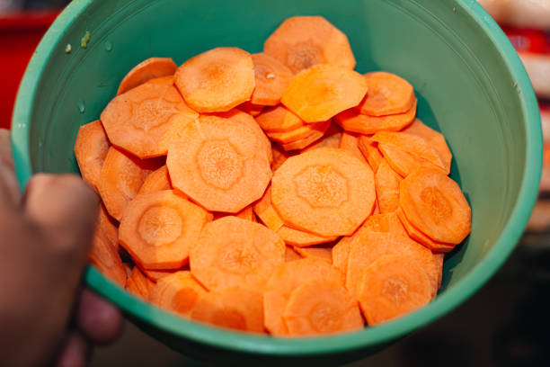 hand taking some pieces of cut carrot in the kitchen