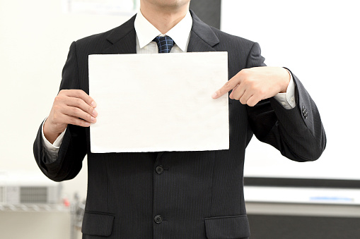 A businessman in a suit holding a message card