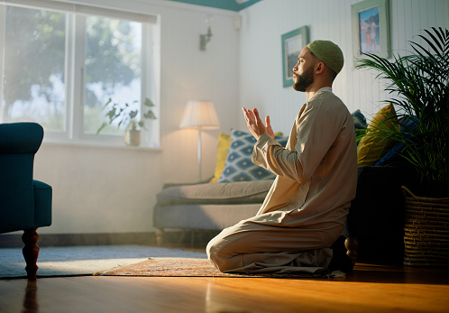 Worship, God and muslim man praying in house with faith, gratitude or spirituality, Islamic, religion or person with duo, dua or prayer hands in living room for thank you, praise or respect for Allah