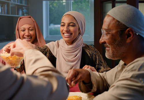 Family, smile and food for Ramadan feast, Muslim people at dinner table together eating, laughing and talking. Islam, men and women with culture, celebration or happy festival of eid al fitr in home