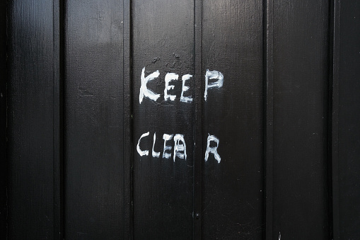 Keep clear sign written on a black garage door