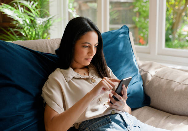 istock Phone, relax and woman on sofa in home online for typing text message, communication and contact on weekend. Happy, chat and person on smartphone for social media, website and internet in living room 2149054527