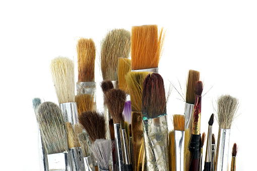 Paintbrushes varying sizes and bristle styles include flat to round and others with wooden handles isolated on white background