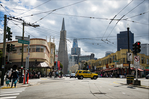 San Francisco, CA, U.S.A. - March 30, 2024: Photo of a large intersection at Stockton Street in North Beach, with view of taxi and the iconic Transamerica Pyramid building on Columbus Ave.