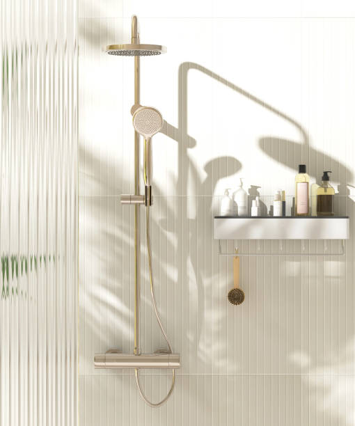 istock Gold rain shower, adjustable shower head, green palm tree, reeded fluted glass partition in sunlight on cream wall bathroom 2149057396