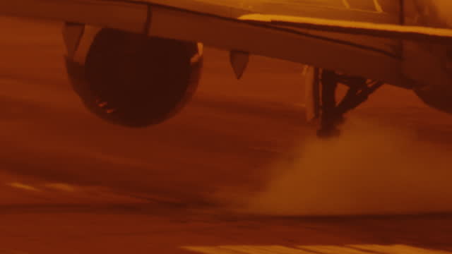smoke on wheel of airplane jet while landing on airstrip of airport close up slow motion