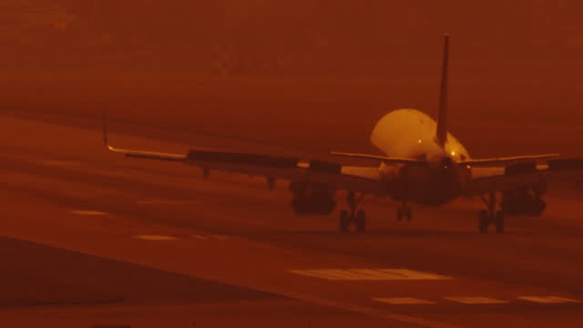 front view of airfreight airplane landing on airstrip of airport with white smoke from wheel