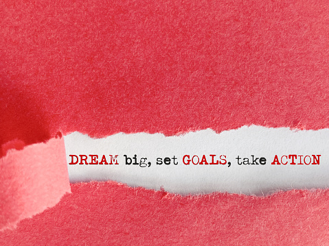 Inspirational motivational concept - dream big set goals take action text behind torn paper background. Stock photo.