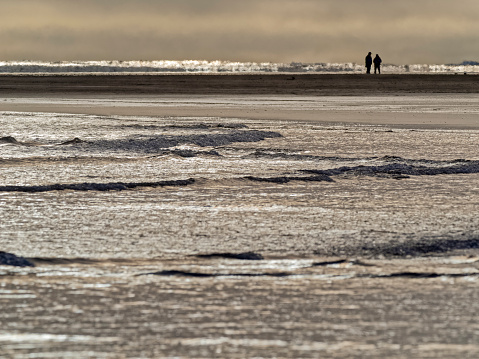 Unrecognizable couple walking along the shoreline of Pacific Rim National Park on Vancouver Island, British Columbia