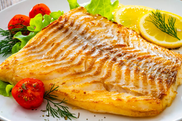 istock Fried cod fillet and fresh vegetables on wooden table 2149059344