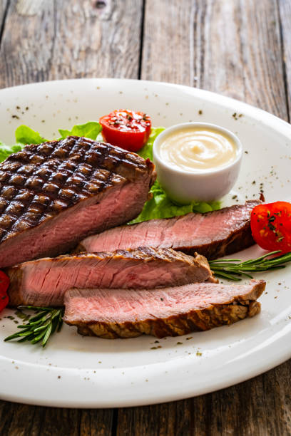 istock Grilled beef sirloin steak with fresh vegetables on wooden table 2149060037