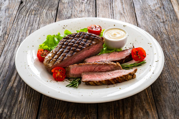 Grilled beef sirloin steak with fresh vegetables on wooden table