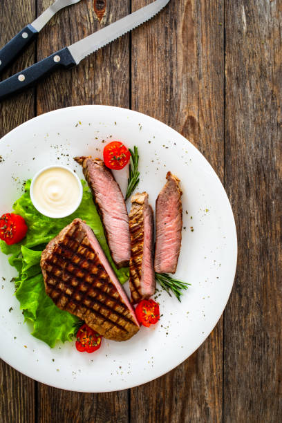 istock Grilled beef sirloin steak with fresh vegetables on wooden table 2149060062