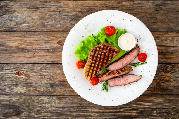 istock Grilled beef sirloin steak with fresh vegetables on wooden table 2149060073