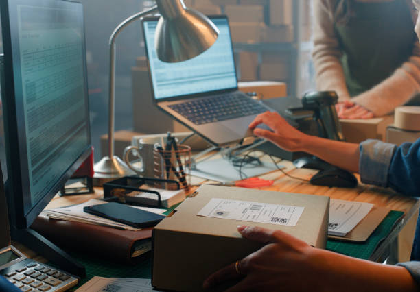 istock Ecommerce, small business and hands in warehouse with boxes, label and teamwork at creative startup. Distribution, online shop and partnership together with laptop, sales or package for dropshipping 2149061731