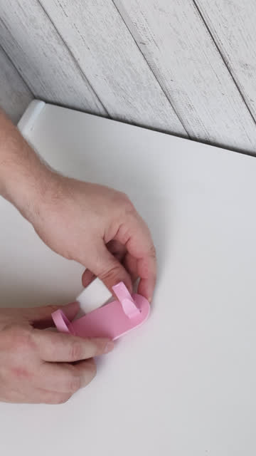 The man makes unpacking and reviewing the purchase. Trys the device to the wall. Plastic wall mount for an electric brow or brush. Vertical video. Close-up.