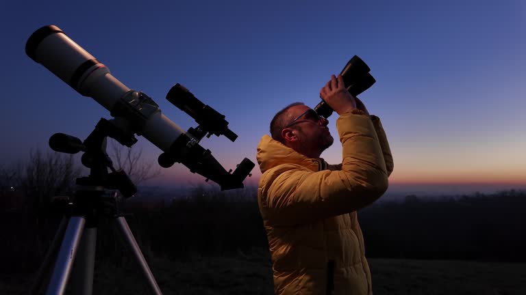 Amateur astronomer looking at the evening skies, observing planets, stars, Moon and other celestial objects with a telescope and binoculars.