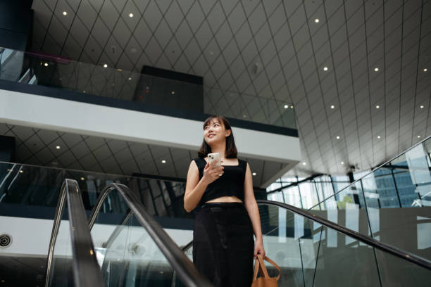 istock Young Asian woman using smartphone while riding on escalator in MRT train station. Business and travel concept. 2149065234