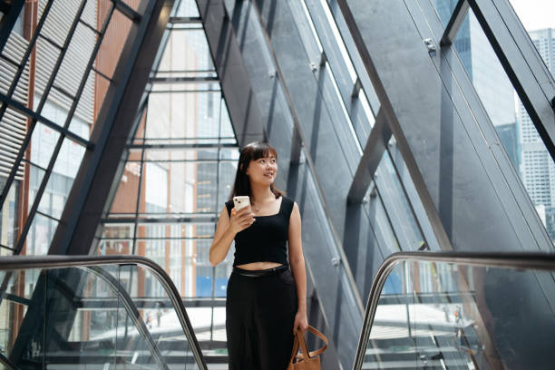 istock Young Asian woman using smartphone while riding on escalator in MRT train station. Business and travel concept. 2149065237