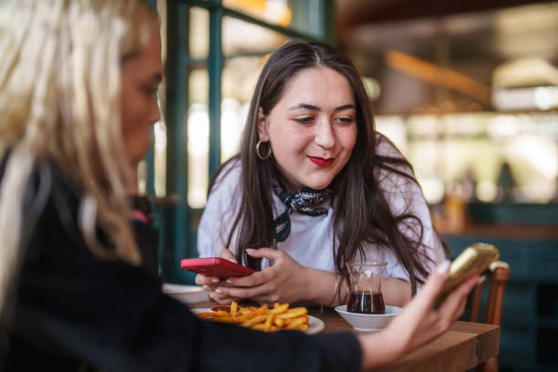 istock Two women using mobile phones in a cafe. 2149066267