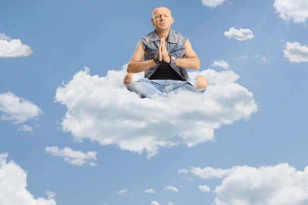 istock Man sitting corssed legged and practicing meditation on a cloud in the sky 2149066270