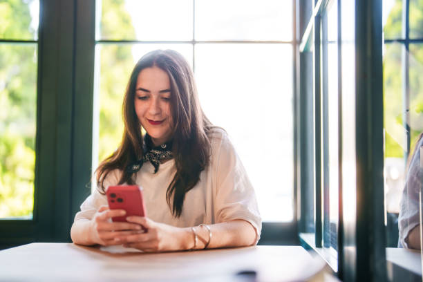 istock Young woman using mobile phone on table in a restaurant. 2149066392