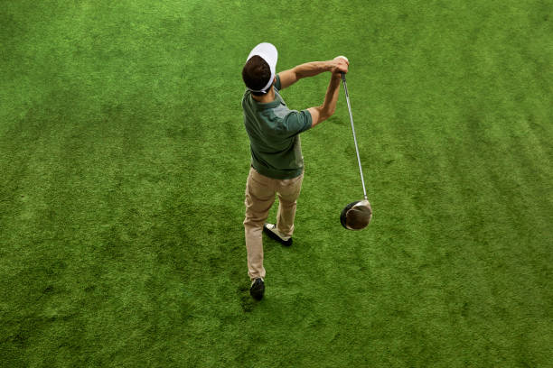 istock Aerial view of skilled golfer in casual attire, in cap doing completing swing in motion on green turf. 2149066607