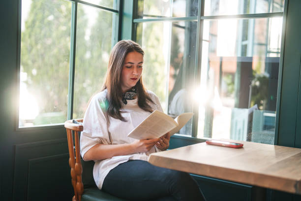 istock Young woman reading a book in cafe. 2149066961