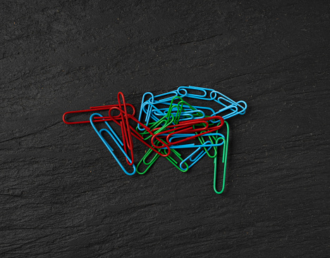 Note Paper Clips, Color Clips, Paperclips Pile, Colorful Stationary, Paperclips Office Equipment on Black Background with Copy Space for Text Top View