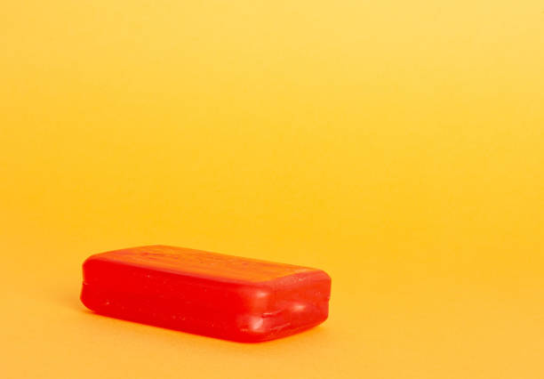 Red Soap Bar, Body Care Cosmetic, Fruit Flavored Soapy Detergent, Solid Shampoo, Red Translucent Glycerin Soap on Yellow Background