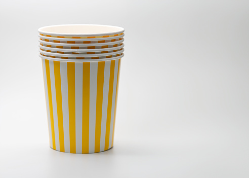 Disposable stacked of paper bucket with yellow and white stripes, empty popcorn buckets isolated on white background.