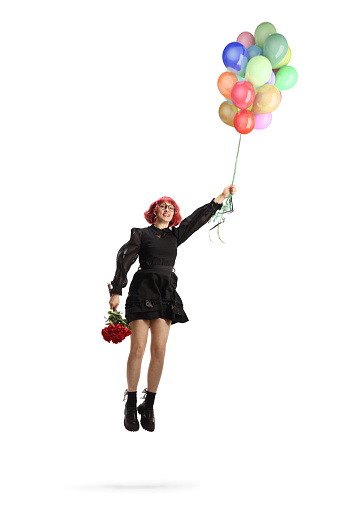 Woman in a black dress with red roses flying and holding a bunch of balloons isolated on white background