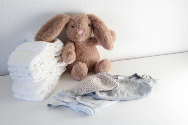 istock A stack of diapers, onesies and a plush bunny on white changing table 2149070415