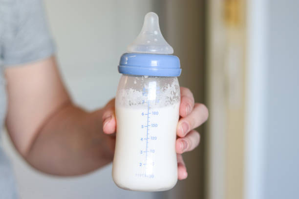 istock Mothers hand holding feeding bottle with baby formula milk 2149070609