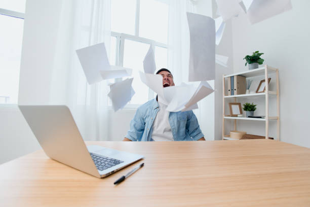 istock Crazy screaming irritated handsome stylish young businessman throws the paper over the table out of anger. Copy space for ad. Remote Job, Technology And Career Profession Concept 2149071168
