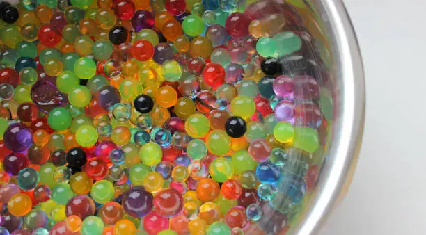 Heap Of Multicolor Water Beads On Curved Steel Surface