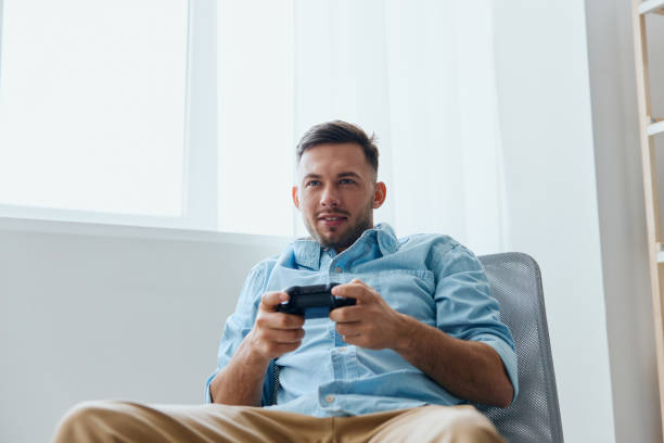 istock Overjoyed focused young tanned enthusiastically play with joystick gamepad at home interior. Player Stream Platform Gamers concept. Relaxing Active recreation. Copy space for game console advertising 2149071717