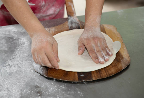 istock Man's hands preparing pizza dough on wooden tray 2149071930