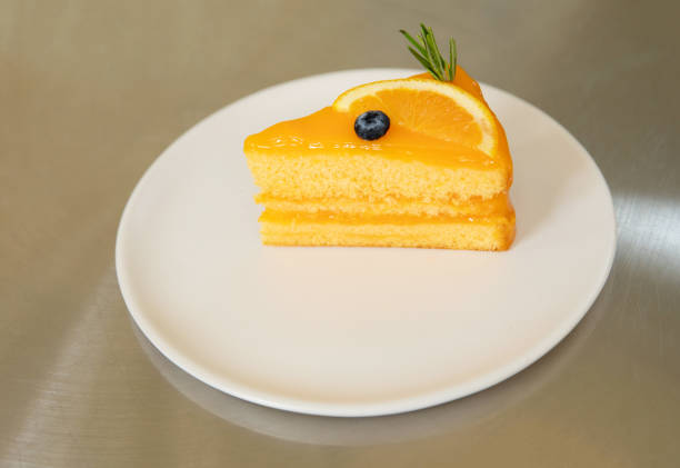 Piece of orange cake in white dish on the stainless table background