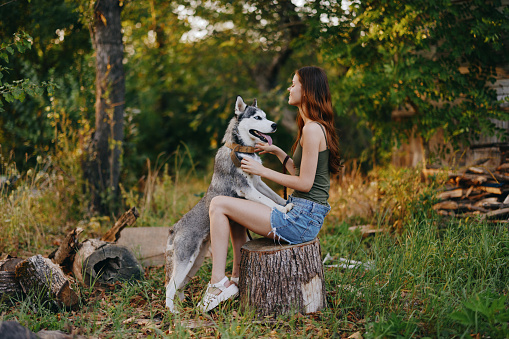 Woman and her husky dog happily playing outdoors in the park among the trees smile with teeth in the autumn walk with her pet. High quality photo