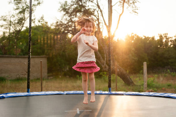 Little girl jumping on a trampoline in the backyard