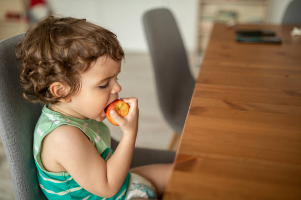 istock LIttle boy eating apple indoors 2149074713