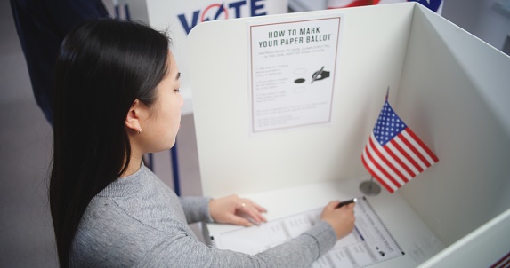 Asian woman at US voting booth.