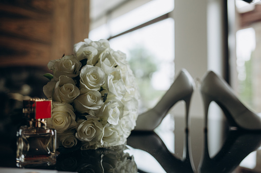 Bridal bouquet, bride shoes and earings on chair, copy space. Luxury wedding accessories and jewelry. Wedding concept.