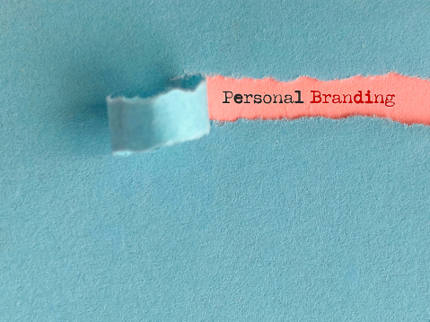 Personal branding text behind torn paper background. Stock photo.