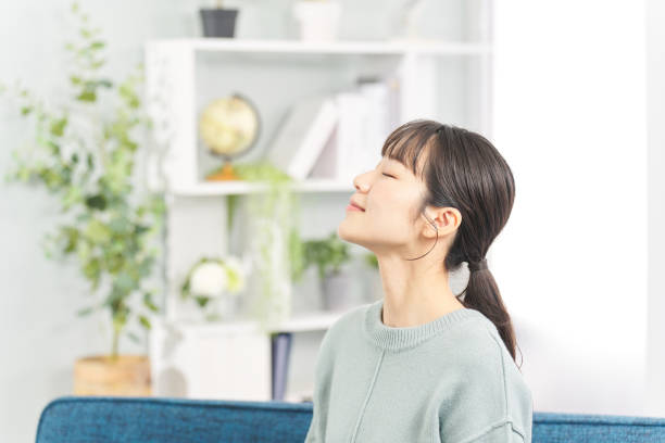 居間で目を閉じる女性 - リフレッシュ ストックフォトと画像